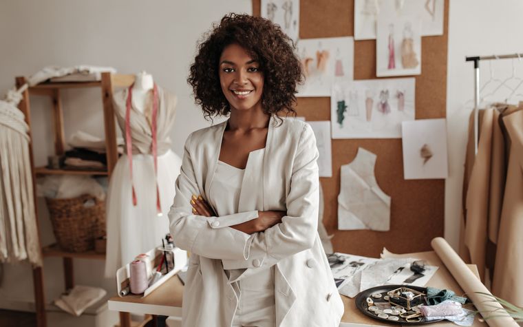 Fondatrice de petite entreprise souriante, bras croisés, dans son atelier de création